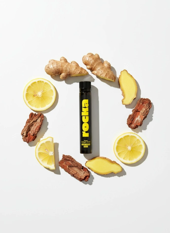 Vegan Collagen Boost ampoule surrounded by fresh ginger roots and lemon slices representing natural ingredients